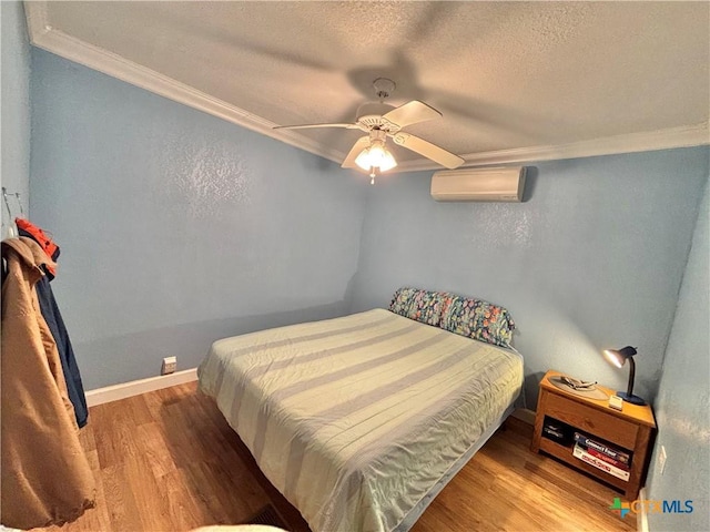 1306 W Madison Ave, Port Oconnor, TX 77982 - bedroom with a wall mounted AC, crown molding, wood finished floors, a textured ceiling, and a ceiling fan
