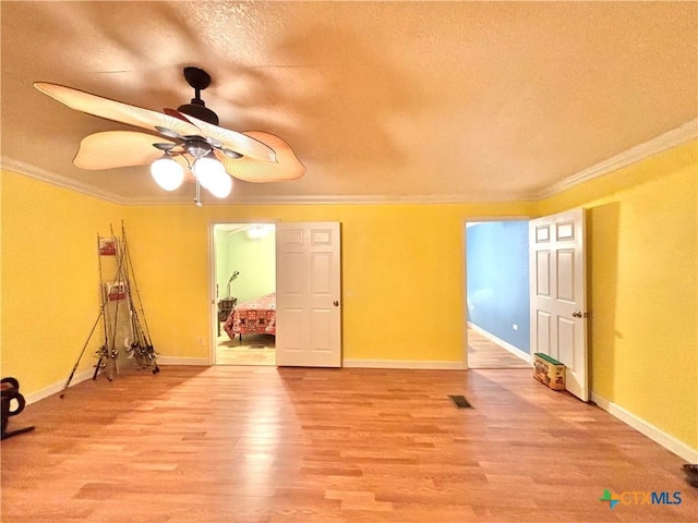 1306 W Madison Ave, Port Oconnor, TX 77982 - unfurnished room featuring ornamental molding, light wood finished floors, baseboards, a textured ceiling, and a ceiling fan