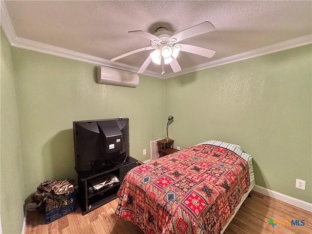 1306 W Madison Ave, Port Oconnor, TX 77982 - bedroom featuring a wall mounted AC, ornamental molding, wood finished floors, a textured ceiling, and baseboards