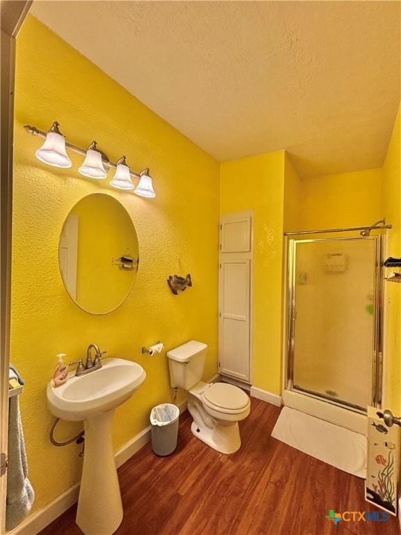 1306 W Madison Ave, Port Oconnor, TX 77982 - full bathroom with wood finished floors, a shower stall, baseboards, toilet, and a textured ceiling