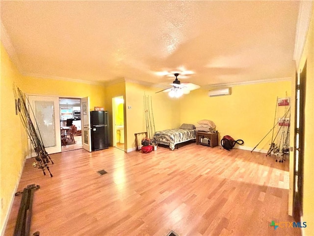 1306 W Madison Ave, Port Oconnor, TX 77982 - unfurnished bedroom with a wall mounted AC, freestanding refrigerator, light wood-type flooring, ornamental molding, and a textured ceiling