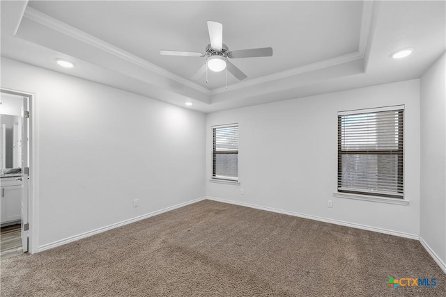 carpeted spare room featuring crown molding, ceiling fan, and a tray ceiling