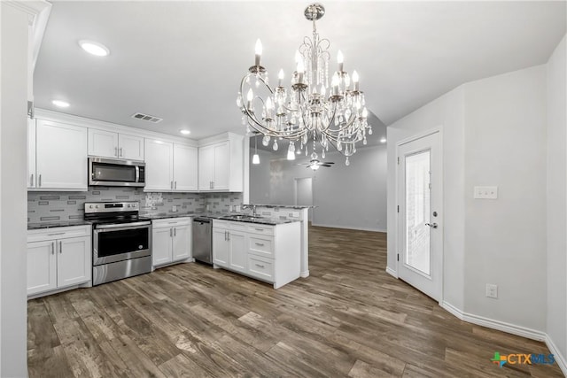 kitchen with sink, hanging light fixtures, appliances with stainless steel finishes, decorative backsplash, and white cabinets