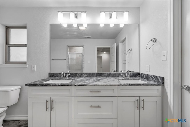 bathroom with vanity, toilet, and a shower with door