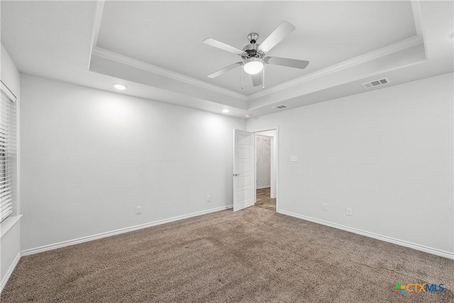 carpeted spare room featuring a raised ceiling, ornamental molding, and ceiling fan