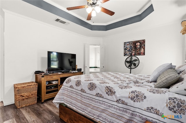 bedroom featuring dark wood finished floors, crown molding, a raised ceiling, and a ceiling fan