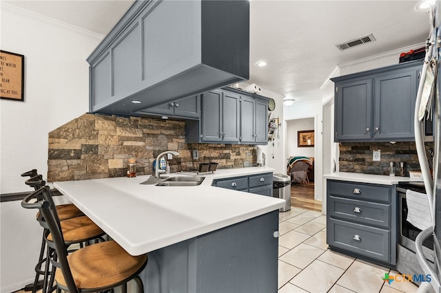 kitchen featuring a sink, ornamental molding, backsplash, a peninsula, and a kitchen breakfast bar