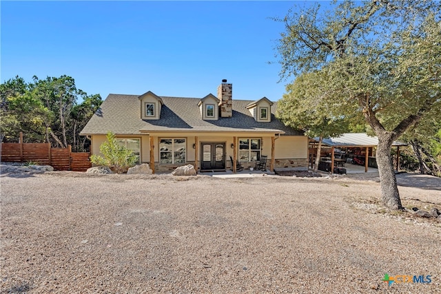 cape cod home with french doors and a carport