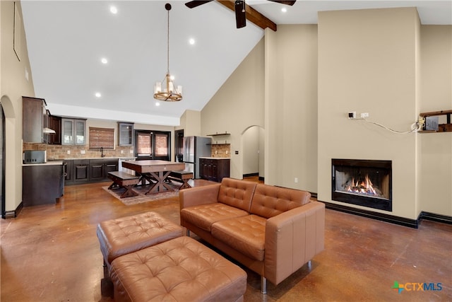 living room featuring beamed ceiling, ceiling fan with notable chandelier, high vaulted ceiling, and sink