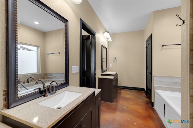 bathroom with vanity, a bathtub, and concrete floors