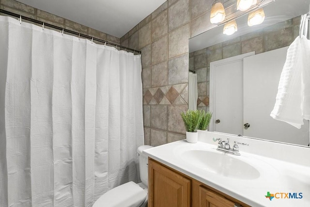 bathroom featuring tile walls, toilet, and vanity