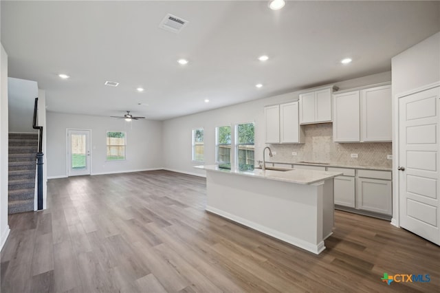 kitchen featuring hardwood / wood-style floors, sink, ceiling fan, an island with sink, and white cabinetry