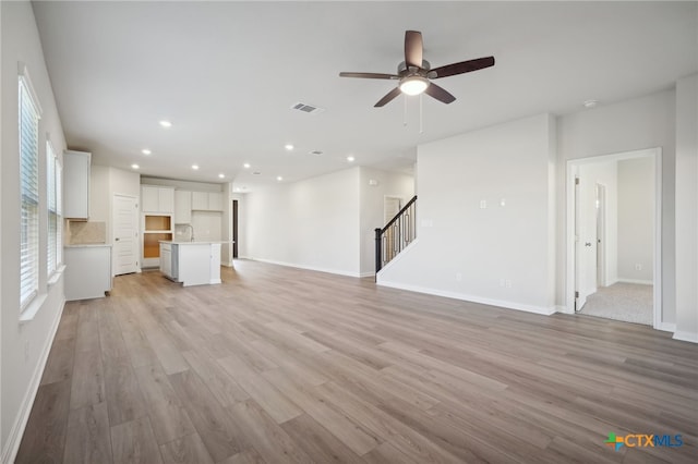 unfurnished living room featuring ceiling fan, light wood-type flooring, and sink