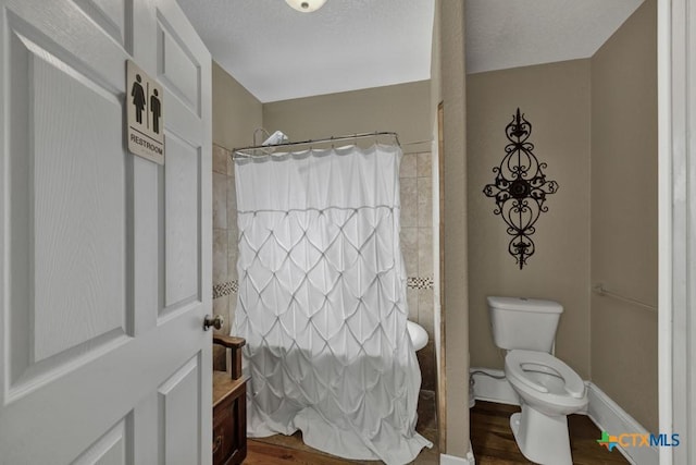 608 S Guadalupe St, San Marcos, TX 78666 - full bathroom with wood finished floors, a shower with curtain, vanity, and a textured ceiling