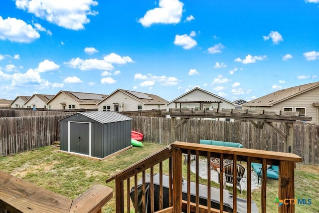 deck featuring a residential view, a storage shed, a fenced backyard, a yard, and an outbuilding