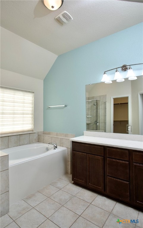 bathroom featuring vanity, independent shower and bath, tile patterned floors, and vaulted ceiling