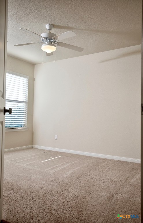 carpeted empty room with ceiling fan and a textured ceiling