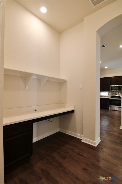 unfurnished office featuring built in desk and dark hardwood / wood-style flooring