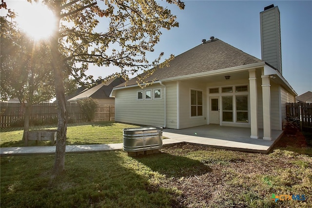 rear view of property with a patio, a yard, and a jacuzzi