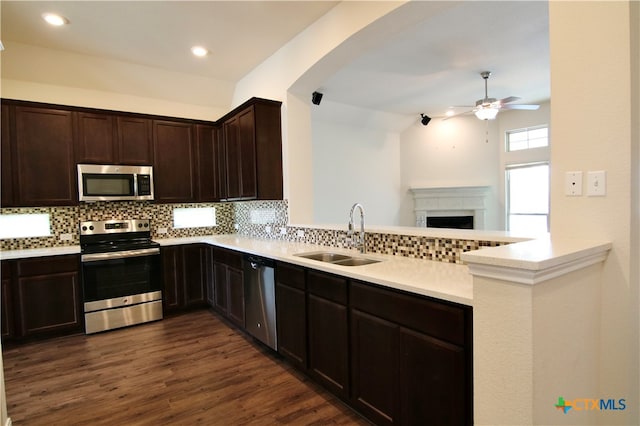 kitchen featuring stainless steel appliances, sink, kitchen peninsula, tasteful backsplash, and dark hardwood / wood-style flooring