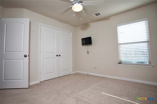 unfurnished bedroom featuring ceiling fan, light carpet, and a closet