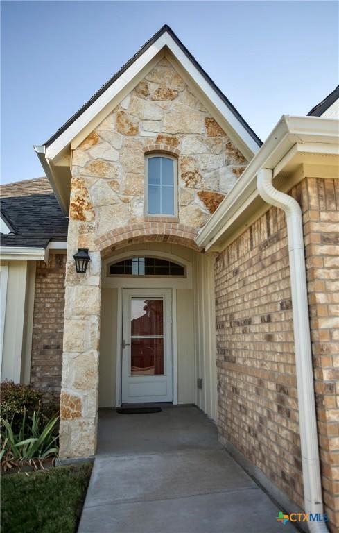7841 Old Gate Rd, Temple, TX 76502 - entrance to property with stone siding, a shingled roof, and board and batten siding