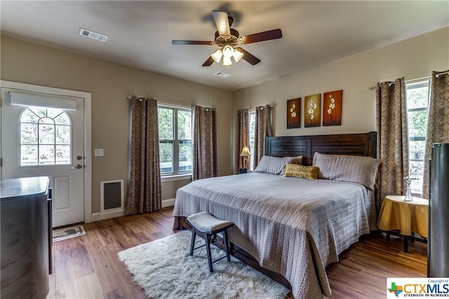 bedroom with wood-type flooring, multiple windows, and ceiling fan