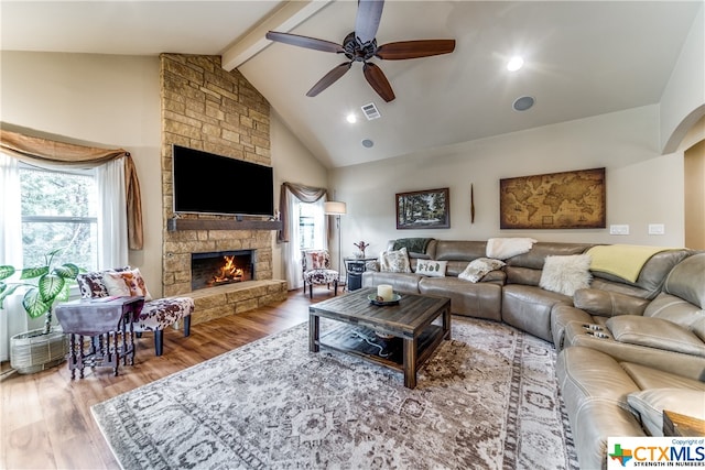 living room featuring high vaulted ceiling, a stone fireplace, ceiling fan, beamed ceiling, and wood-type flooring