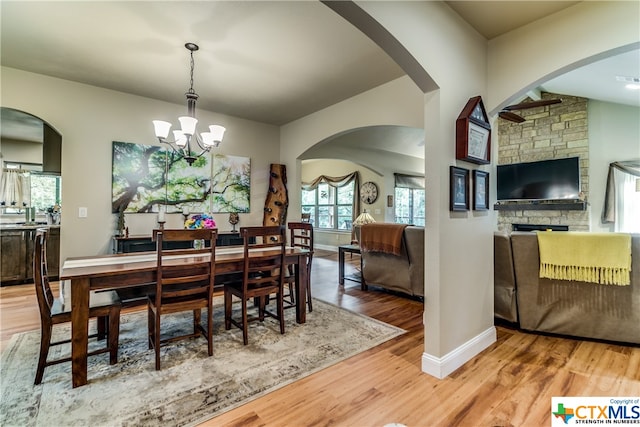 dining space with hardwood / wood-style flooring, a fireplace, and an inviting chandelier