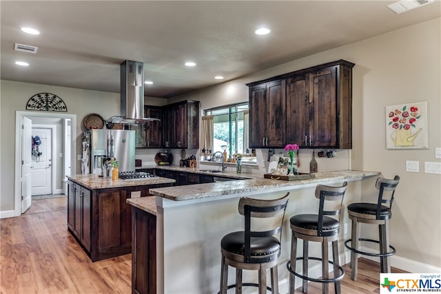 kitchen with light hardwood / wood-style floors, island range hood, kitchen peninsula, and stainless steel appliances