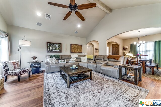 living room featuring hardwood / wood-style floors, ceiling fan with notable chandelier, high vaulted ceiling, and beam ceiling