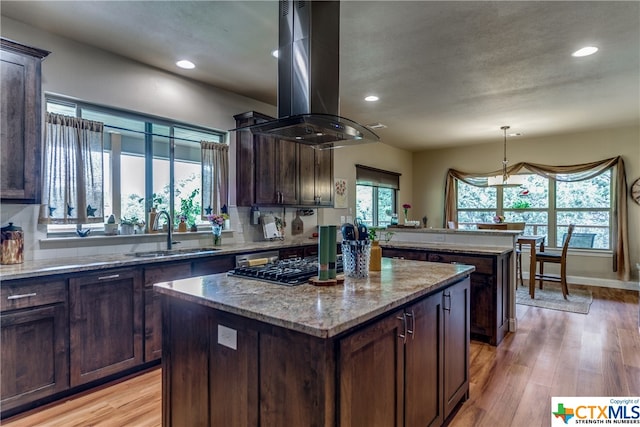 kitchen with a center island, island range hood, a healthy amount of sunlight, and light hardwood / wood-style flooring