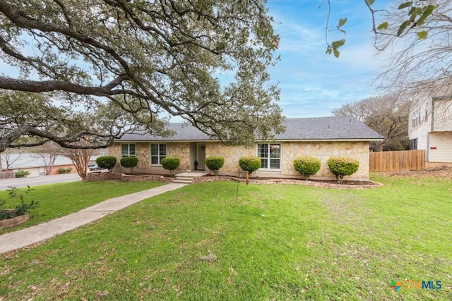 ranch-style house featuring stone siding, fence, and a front yard