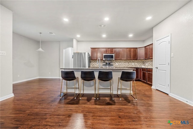 606 Hobby Rd, Copperas Cove, TX 76522 - kitchen with stainless steel appliances, decorative backsplash, an island with sink, a breakfast bar, and a sink