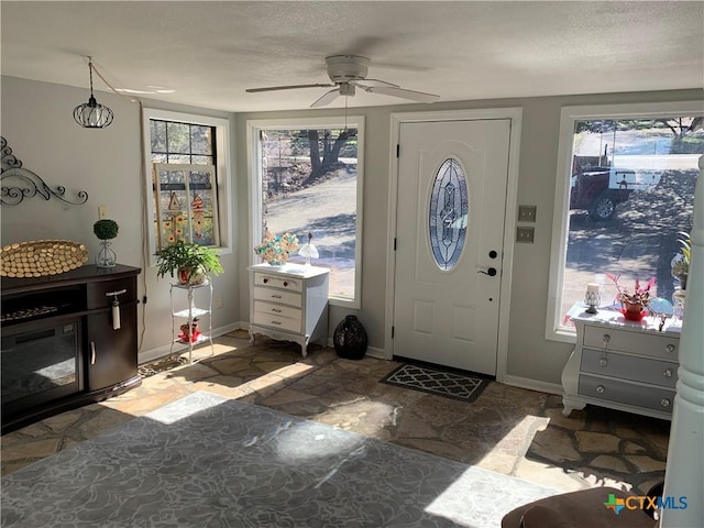 entryway with a ceiling fan, a textured ceiling, and baseboards