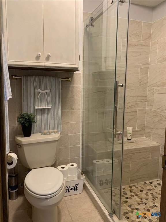 bathroom with tile walls, toilet, tile patterned flooring, and a stall shower