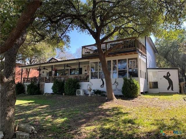 back of house featuring a balcony, ac unit, a ceiling fan, and a yard