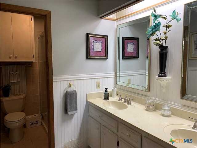 full bath featuring a shower, wainscoting, a sink, and toilet