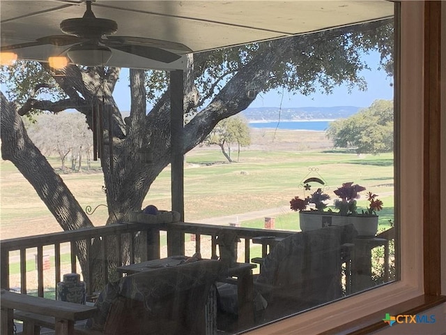 deck featuring ceiling fan, a lawn, and a water view