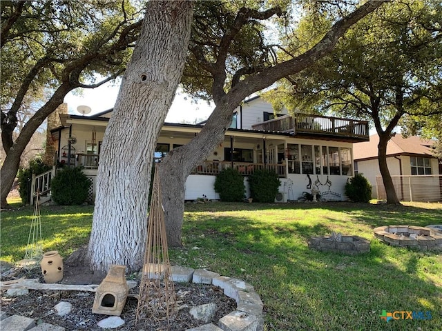 view of front of home featuring an outdoor fire pit, a balcony, and a front lawn