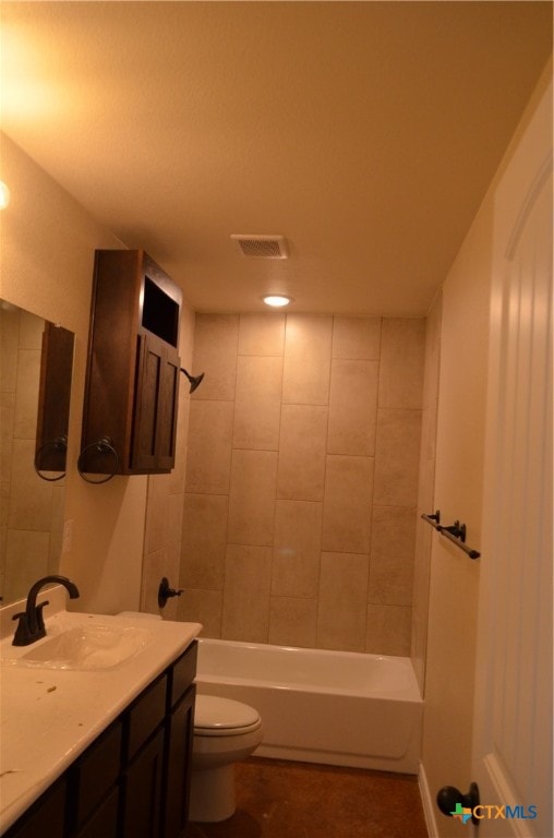 full bathroom featuring vanity, tiled shower / bath, and toilet