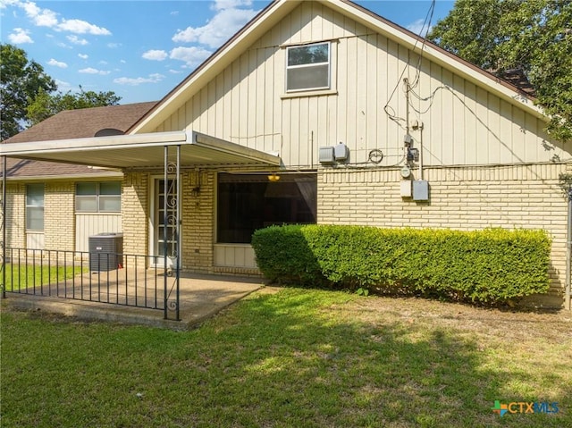 back of house with brick siding and a lawn