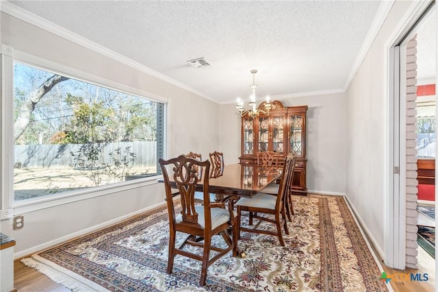 dining area featuring a notable chandelier, a healthy amount of sunlight, visible vents, and light wood-type flooring