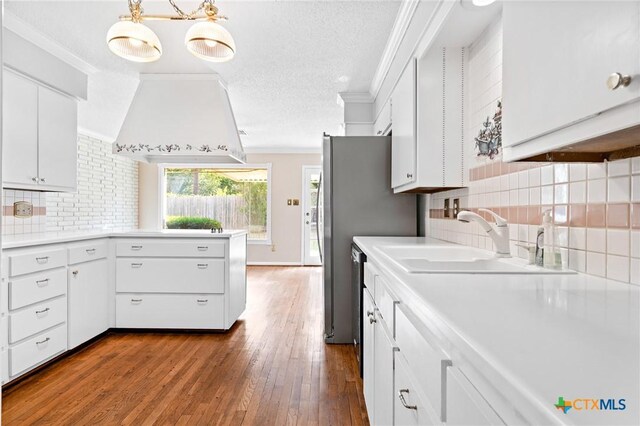 kitchen with dark wood-type flooring, ornamental molding, a sink, white cabinets, and light countertops