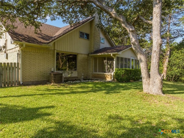 mid-century modern home with cooling unit, brick siding, a front lawn, and fence