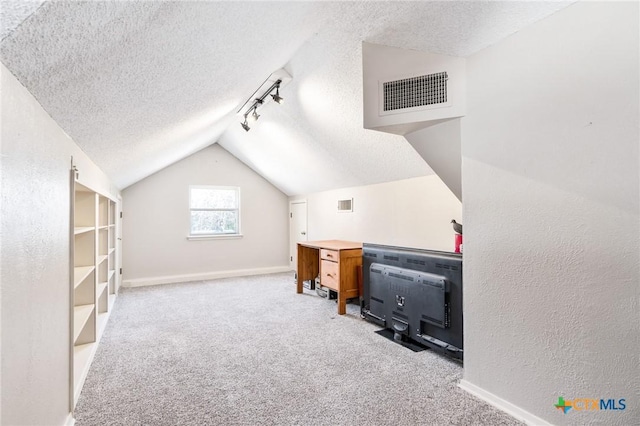 carpeted office space featuring lofted ceiling, rail lighting, visible vents, and a textured ceiling