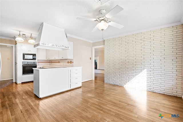 kitchen with premium range hood, light wood-type flooring, black appliances, white cabinetry, and light countertops