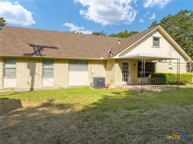 back of house featuring a patio, cooling unit, a yard, a shingled roof, and brick siding