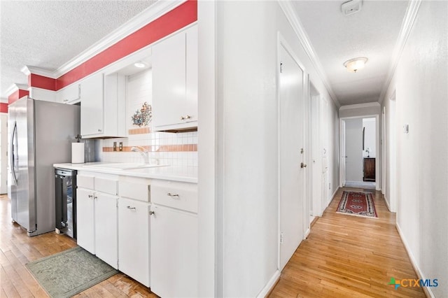 kitchen featuring a sink, light wood-style floors, freestanding refrigerator, and ornamental molding