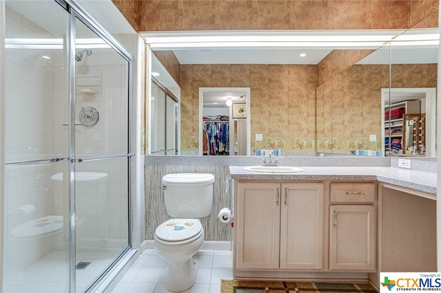 bathroom featuring toilet, vanity, tile patterned flooring, and a shower with door